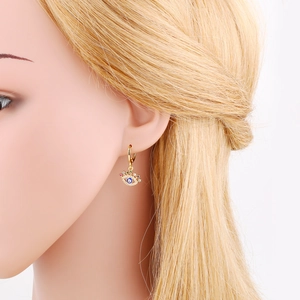Close-up of golden evil eye hoop earring with colorful zircons on model ear