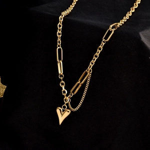 Detail of vintage heart pendant on a gold mixed link chain over a dark background