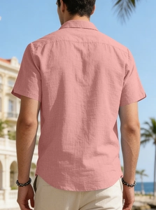 Rear view of a men's pink short-sleeved casual shirt with a resort-style palm tree background