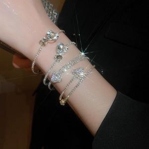 Close-up of sparkling zircon heart and geometric arrow bracelets on a wrist