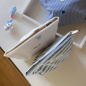 Detail view of canvas cosmetic bags with blue bow embroidery and metal zipper closure