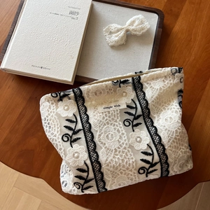 French lace makeup bag with black floral embroidery and Simple Wish label on wooden desk