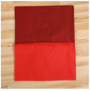 Détail de la housse de chaise de Noël rouge bicolore sur un fond de sol en bois