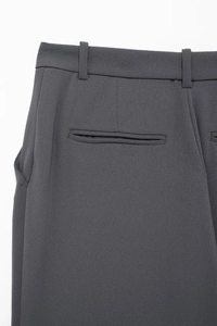 Macro shot of dark grey suit trousers showing rear waist belt loops and welt pocket detail