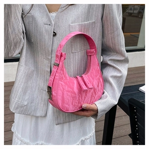 Macro shot of pink pleated texture and metallic buckle on a glossy crescent bag