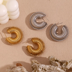 Detail of twisted texture C-shape hoop earrings with zircon pavé edges in gold and silver