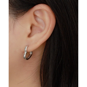 Close-up of polished silver S925 heart hoop earring worn on a model ear lobe
