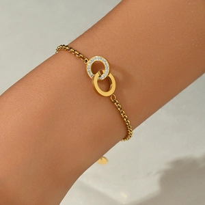Detailed view of intertwined gold double rings with pavé cubic zirconia on the wrist