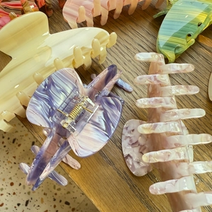 Selection of acetate claw clips in marble purple and floral patterns on a wooden surface