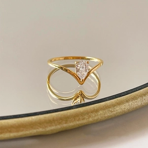 Macro detail of gold V-shaped necklace with pear-cut stone reflecting on a mirror