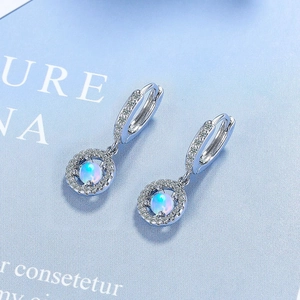 Macro shot of silver opal earrings with zircon inlay showing polished metal details