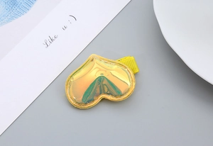 Detail of a heart-shaped hair clip with holographic laser finish and gold metal base