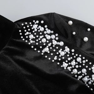 Gros plan sur le tissu en velours noir orné de perles blanches et de textures riches