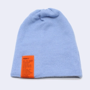 Close-up of ice blue knitted beanie featuring a distinctive orange woven label detail