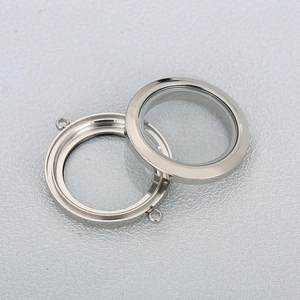 Polished silver stainless steel round glass locket pendant on textured grey background