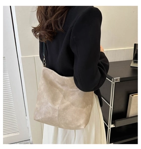 Detailed view of soft beige leather tote bag with wide strap on a model shoulder