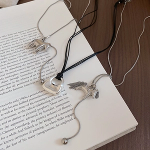 Three minimalist silver necklaces with pony charms displayed on an open book
