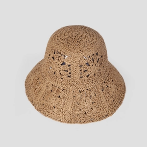 Close-up of khaki woven straw sun hat showing intricate floral crochet patterns