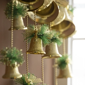 Golden Christmas bell hanging decoration with green pine needles and a ribbon bow
