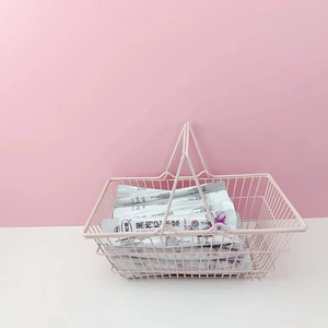Pink metal desktop organizer basket featuring dual handles and compact wire mesh design
