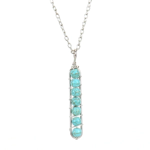 Detail of handmade wire wrapped U-shape pendant with seven turquoise beads and silver chain