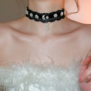 Détail du ras du cou en dentelle noire avec étoiles, lune et pendentif en perle