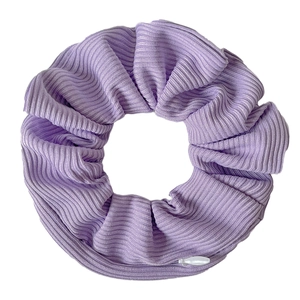 Close-up of a purple tie-dye velvet hair scrunchie showing soft ribbed knit texture detail