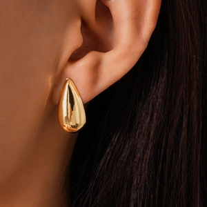 Gros plan de boucles d'oreilles goutte d'or polies avec finition miroir brillante