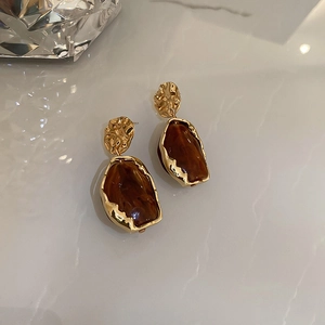 Detail of vintage geometric resin earrings with amber stone and golden metal border
