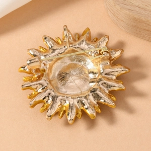 Detail of gold sunflower brooch back with pin clasp and pendant loop on beige fabric