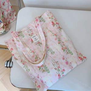 Detail of floral cotton canvas tote bag featuring red flower prints and woven label tag
