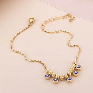 Detail of 18K gold plated evil eye anklet with round beads and lobster clasp on pink background