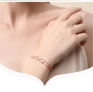 Detail view of rose gold infinity symbol bracelet with clear stones on a model's wrist