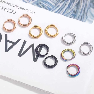 Close-up of assorted stainless steel huggie earrings in gold, silver, black, and rainbow
