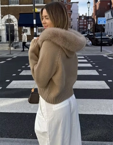 Close-up of a camel hooded knit sweater with a large faux fur collar on city streets