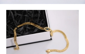 Detailed shot of golden evil eye necklace with blue gem on a white gift box