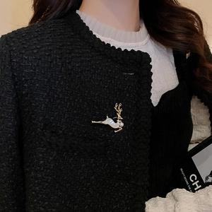 Détail d'une broche renne en nacre et perle portée sur une veste en tweed chic