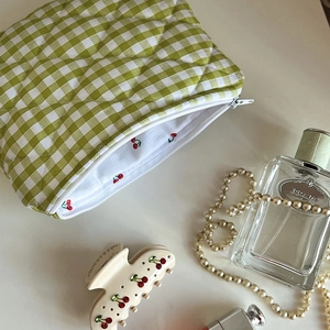 Detail of green checkered quilted makeup bag with cherry print lining and white zipper