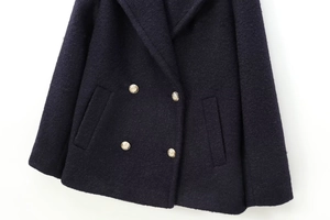 Close-up of double-breasted woolen coat featuring exquisite embossed golden buttons
