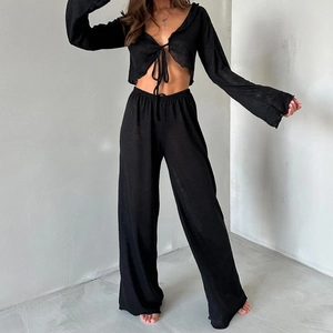 Détail d'un ensemble noir deux pièces avec cardigan court à nouer et pantalon large