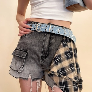 Detail of star-shaped metal cutouts on denim belt with vintage patchwork shorts