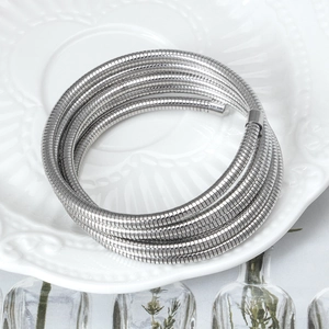 Silver multilayer spring bangle bracelet displayed on a white embossed ceramic plate