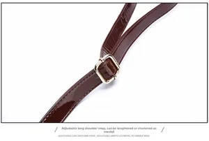 Detail of adjustable dark brown crocodile pattern strap with golden metal square buckle
