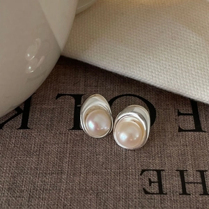 Minimalist 925 sterling silver stud earrings with freshwater pearls on a vintage magazine