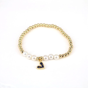 Detail of pearl beaded bracelet with gold beads and blue heart zircon charm pendant