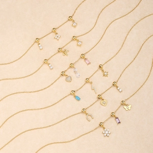 Flat lay of gold charm necklaces with zircon hearts, pearls, and butterfly pendants