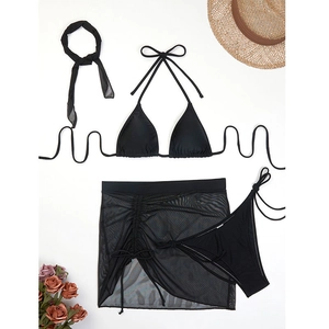 Flat lay of black four-piece bikini set with sheer mesh skirt and vacation accessories