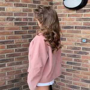 Detailansicht von braunem welligem Haar kombiniert mit einer rosa Wildlederjacke