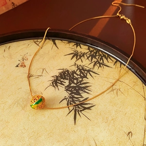 Dettaglio della collana placcata oro 18K con smalto verde su vassoio in bambù