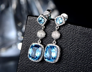 Macro shot of S925 silver drop earrings featuring cushions-cut blue gems and diamond accents